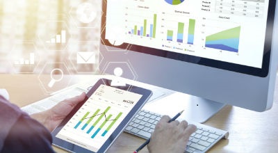 Person using tablet and computer to look at charts and graphs